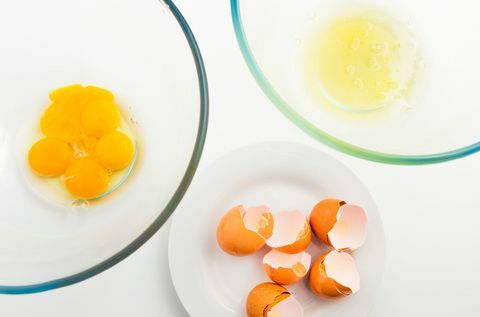 अलग कांच के कटोरे में अंडे की जर्दी और अंडे का सफेद भाग। अंडे और सफेद प्लेट पर अंडा।