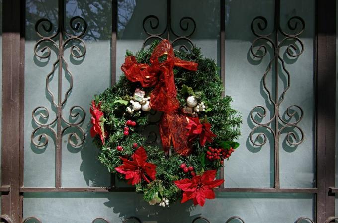 एक सुंदर गढ़ा लोहे और पाले सेओढ़ लिया गिलास सामने वाले दरवाजे पर क्रिसमस पुष्पांजलि