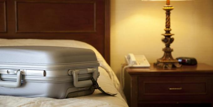 होटल के कमरे में बिस्तर पर सूटकेस