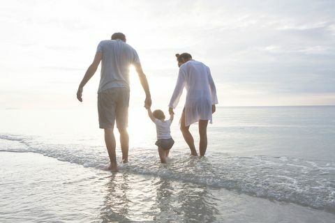 एक परिवार हाथ से हाथ समुद्र तट के नीचे चल रहा है